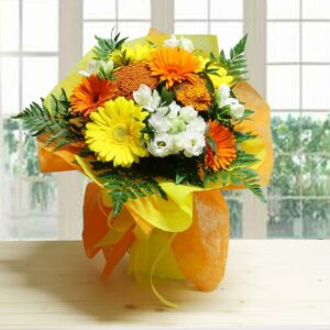 Bouquet Dream Color con Gerbere fresche gialle e arancioni, Fresie bianche e fronde di felce, avvolto in carta regalo gialla e arancione.